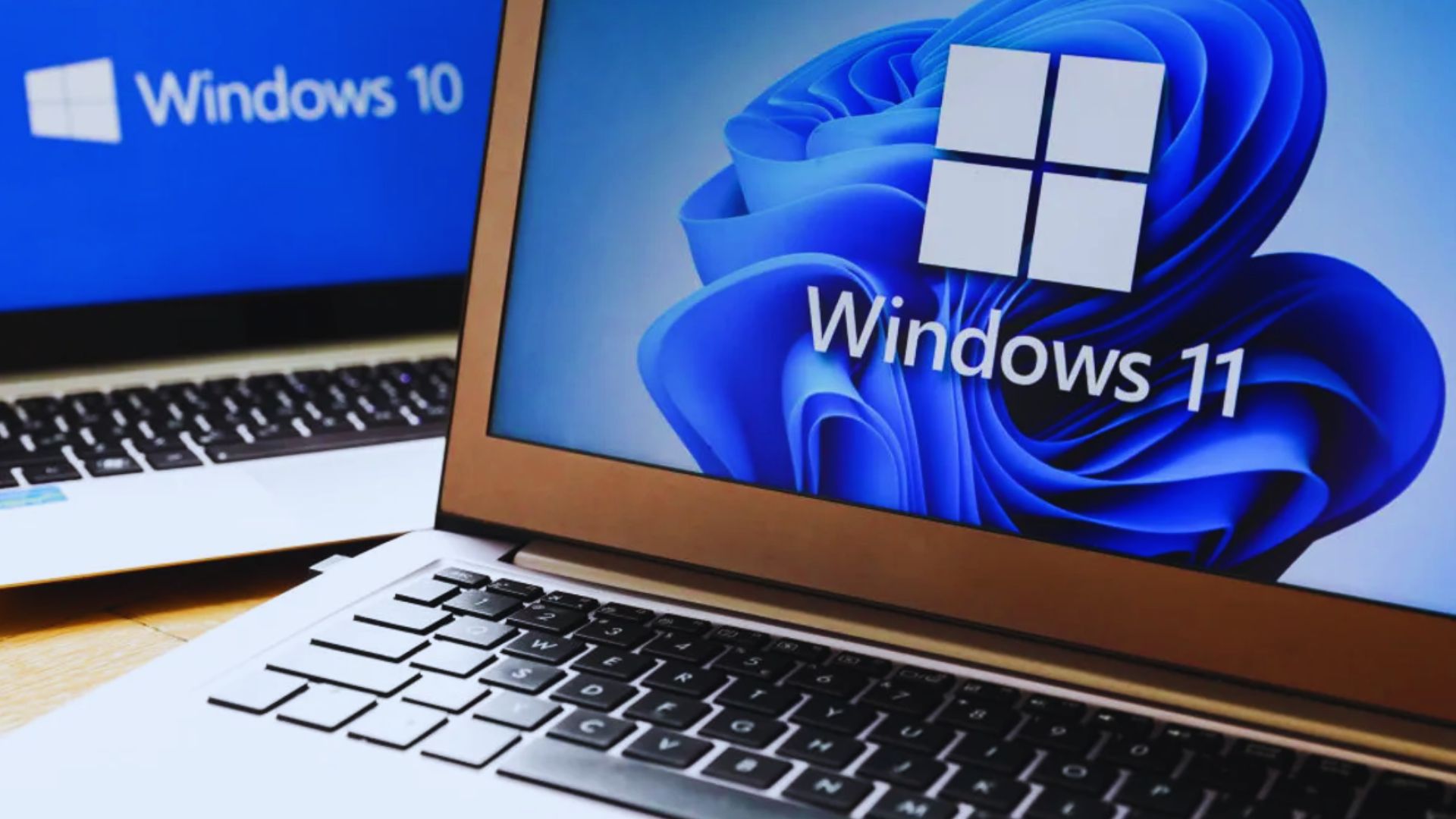 windows 11 logo on laptop in front of another laptop with windows 10 support logo on it