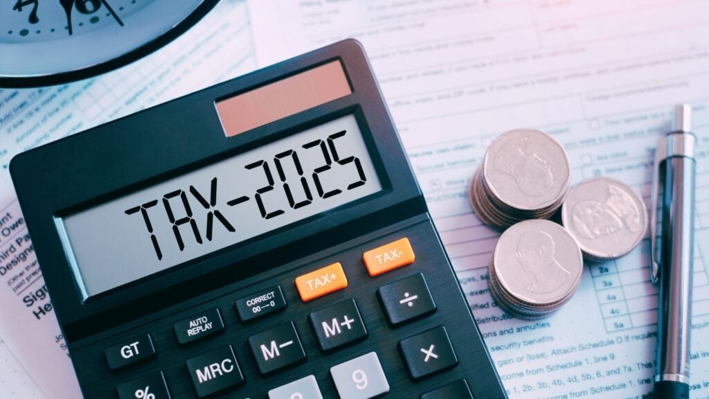 instant asset write-off tax 2025 calculator with coins and pen surrounding a clock with tax forms on desk
