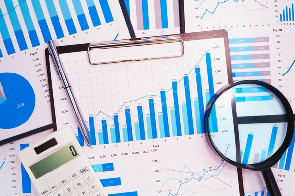 clipboard with column graph pie charts magnifying glass and a calculator on desk signifying business growth