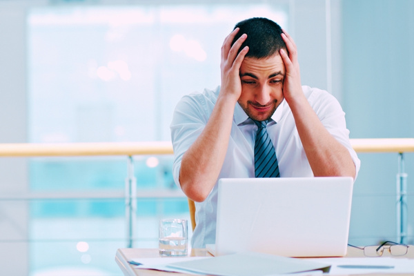 business man wearing a tie looking angry at their laptop due to human cyber risk failure