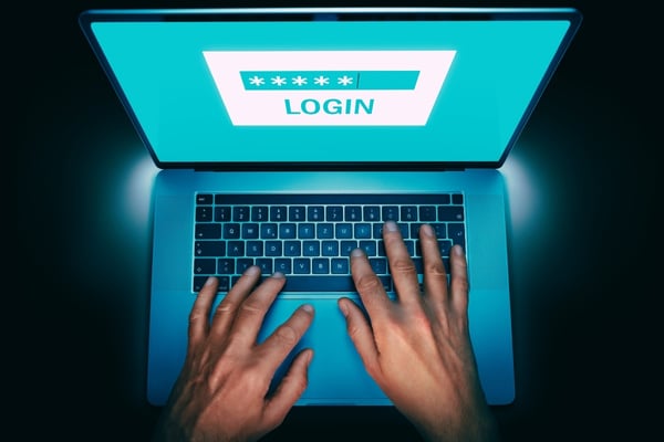 open laptop with a person typing on a login screen requiring a password or passphrase