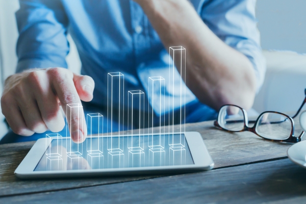 business man pointing at bar graph going up for return on investment with glasses laying on desk