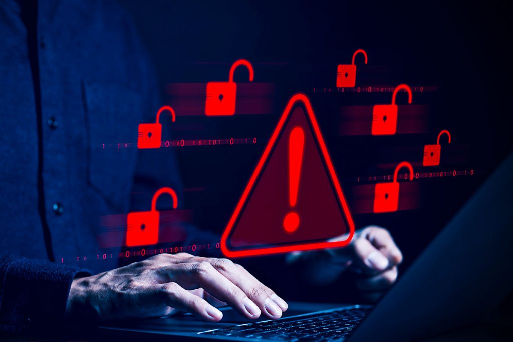 alert symbol hovering over laptop keyboard as hacker types