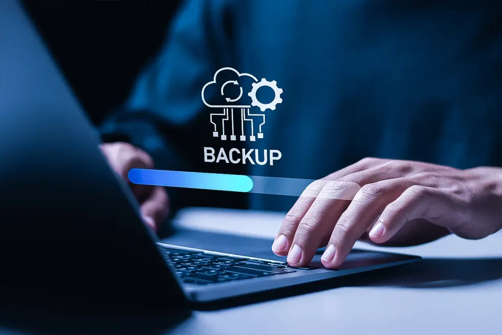 person typing on laptop with a cloud data backup icon hovering over their hands